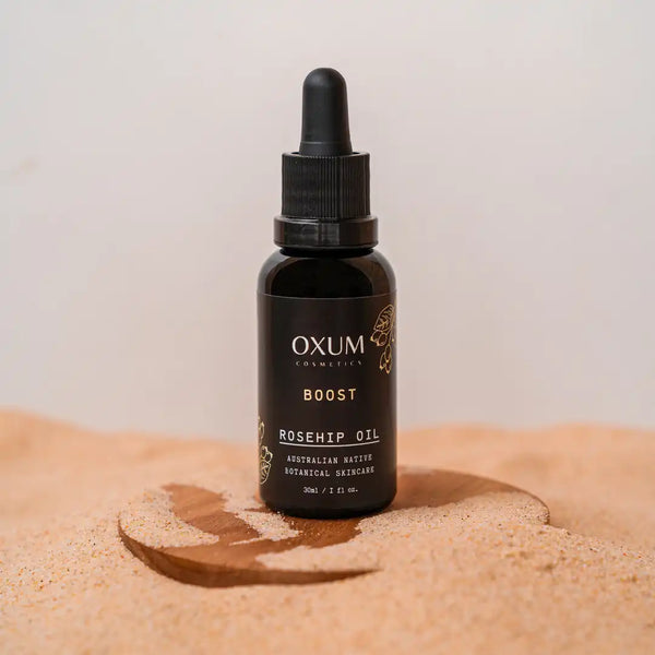 Bottle of Rosehip Oil by Oxum standing in the sand