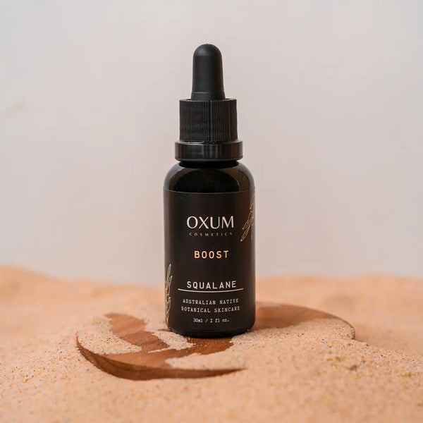 Bottle of Squalane by Oxum standing in the sand