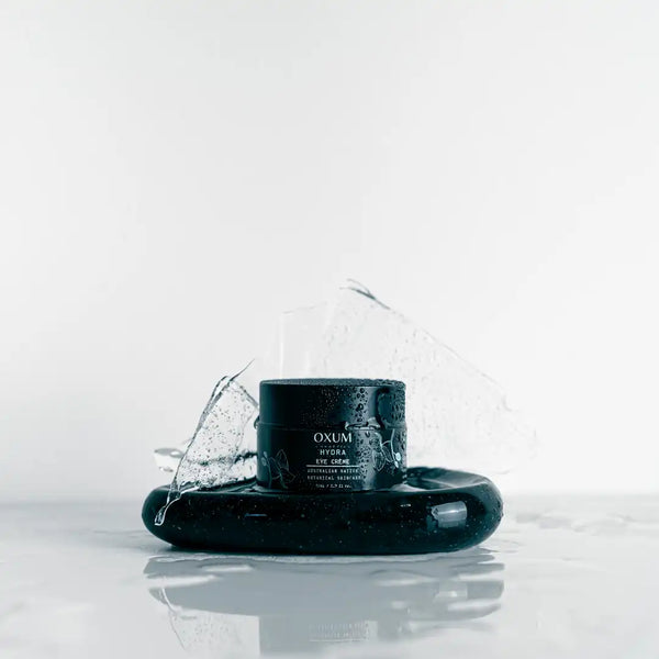 Eye cream jar standing on black stone and ice