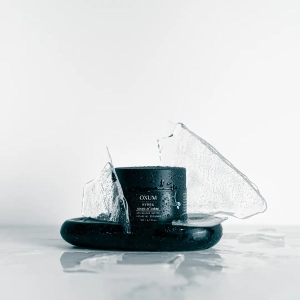 Nourish cream jar standing on black marble and ice